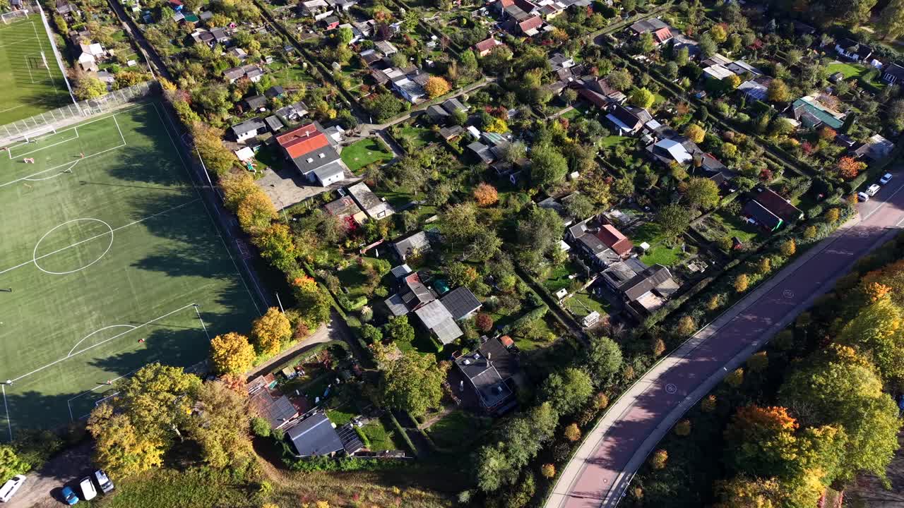 American suburb housing area near soccer field on sunny day in fall season. Aerial top down flyover shot. Houses and homes in idyllic quaint neighborhood in USA