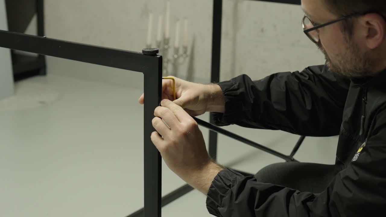 A man assembles a metal frame using an Allen key — concept of DIY, furniture assembly, craftsmanship, and home improvement