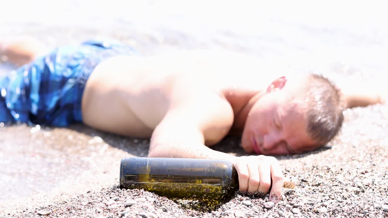 Man passed out on beach with alcohol bottle