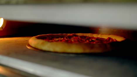 cu cook opens the oven which bakes pizza and turns it