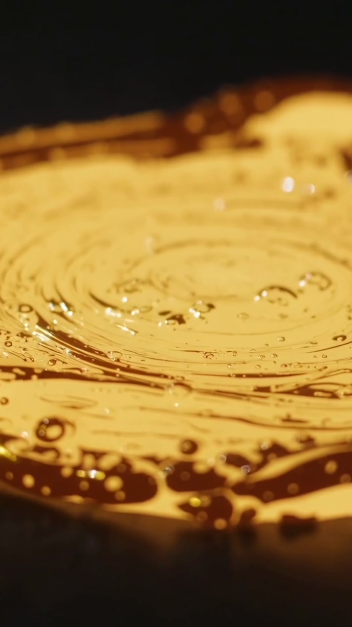 Disturbance forming concentric ripples across warm liquid, bubbles fading, liquid calming, science