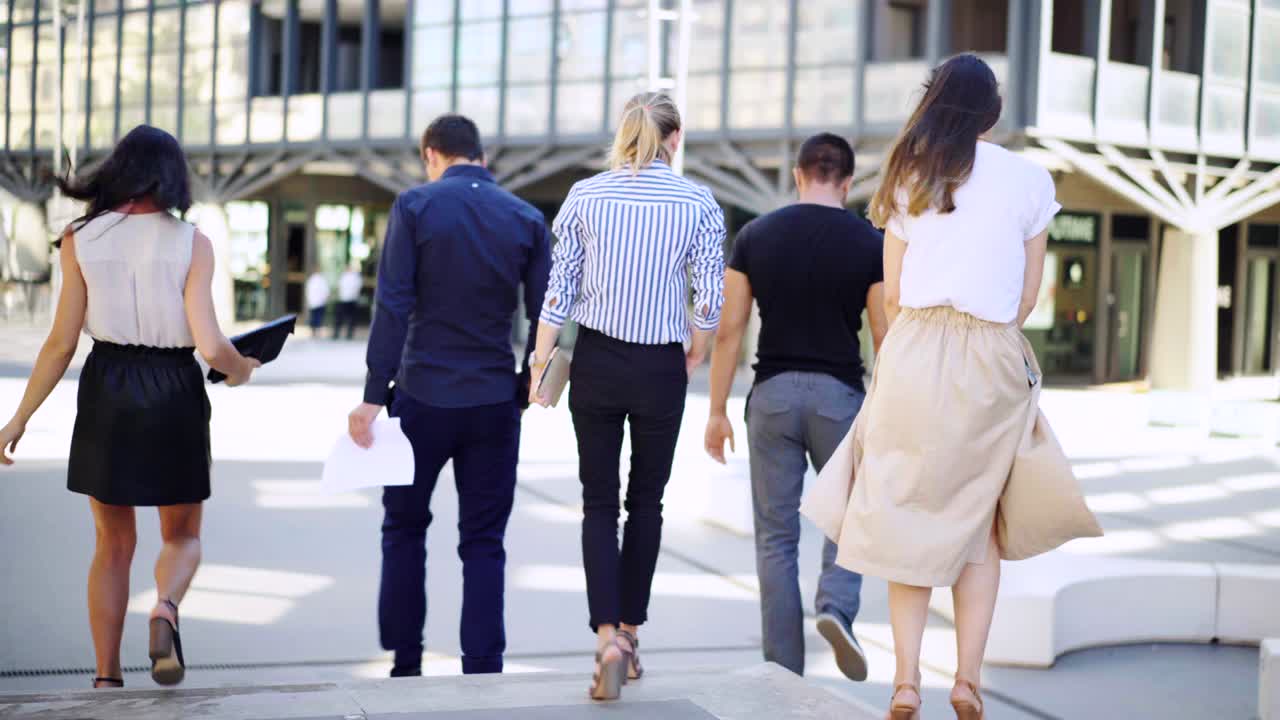 A group of young business people is going to meet. Rear view.Business people having a small talk on their way to the meeting