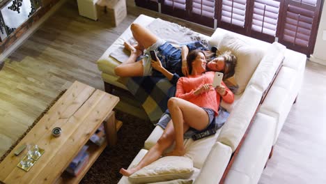 lesbian couple using mobile phone on sofa 4k