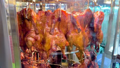 rotating roasted chickens in a market display