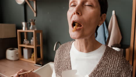woman enjoying takeout noodles in a kitchen