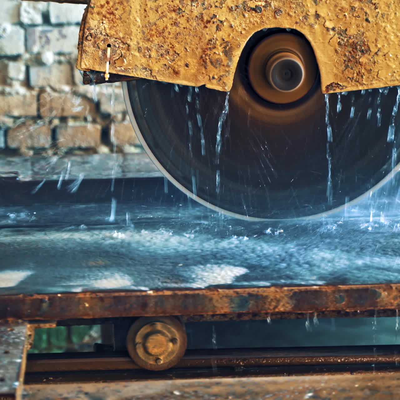 Automated circular saw cuts the stone slab at industrial factory. Process of cutting stove with water. Circle wheel of electric machine for cutting stone slab.