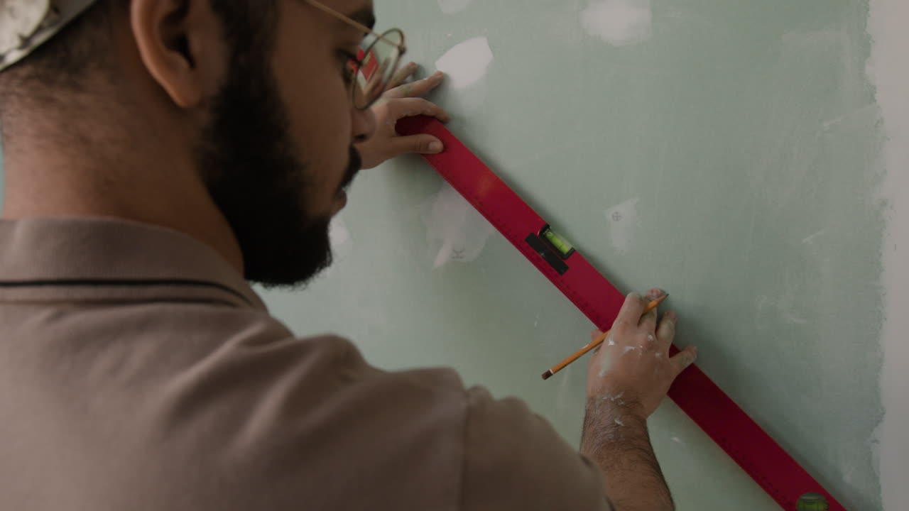 Man uses level on drywall