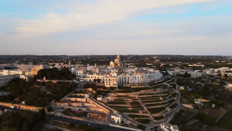 Vista-Panorámica-Aérea-Del-Paisaje-Sobre-Casas-De-Pueblo-De-Locorotondo-Y-Viñedos-En-Terraza,-Ciudad-Tradicional-Italiana-En-La-Cima-De-Una-Colina,-Al-Atardecer