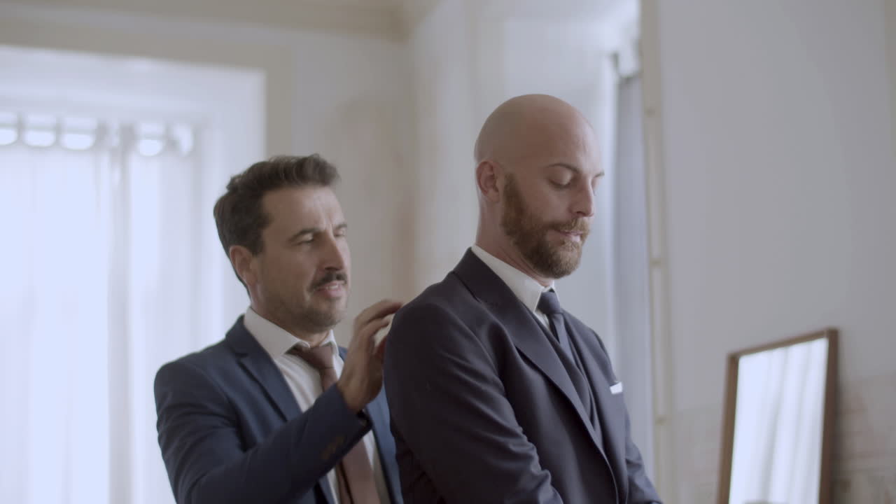 Bell'uomo gay che aiuta il partner a indossare la giacca