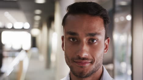 looking confidently at camera, smiling businessman in office hallway