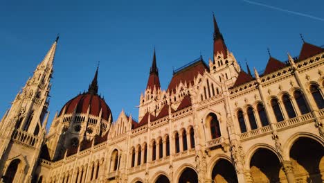 hungary parliament building on the danube river during golden in hand held shot