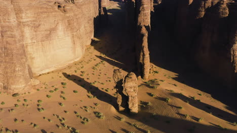 Aerial-tilt-shot-overlooking-steep-canyons-in-middle-of-sandstone-cliffs,-sunset-in-Saudi-Arabia