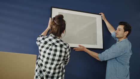 video of couple hanging a picture frame on the wall.