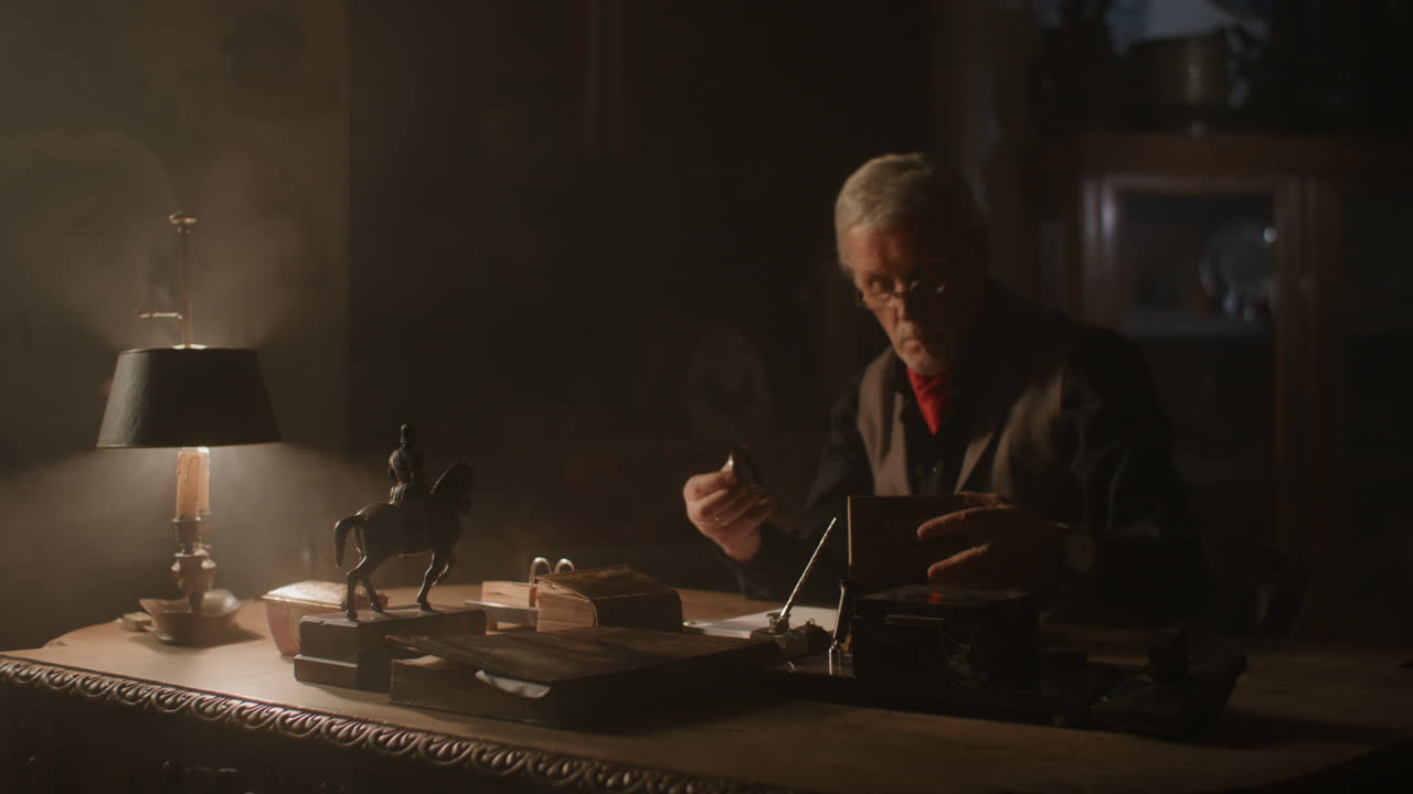 Older passionate man evaluates an old watch in his office at night