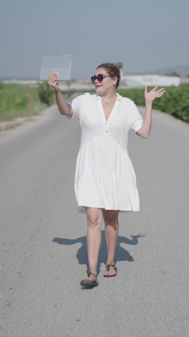 Woman walking on road with laptop