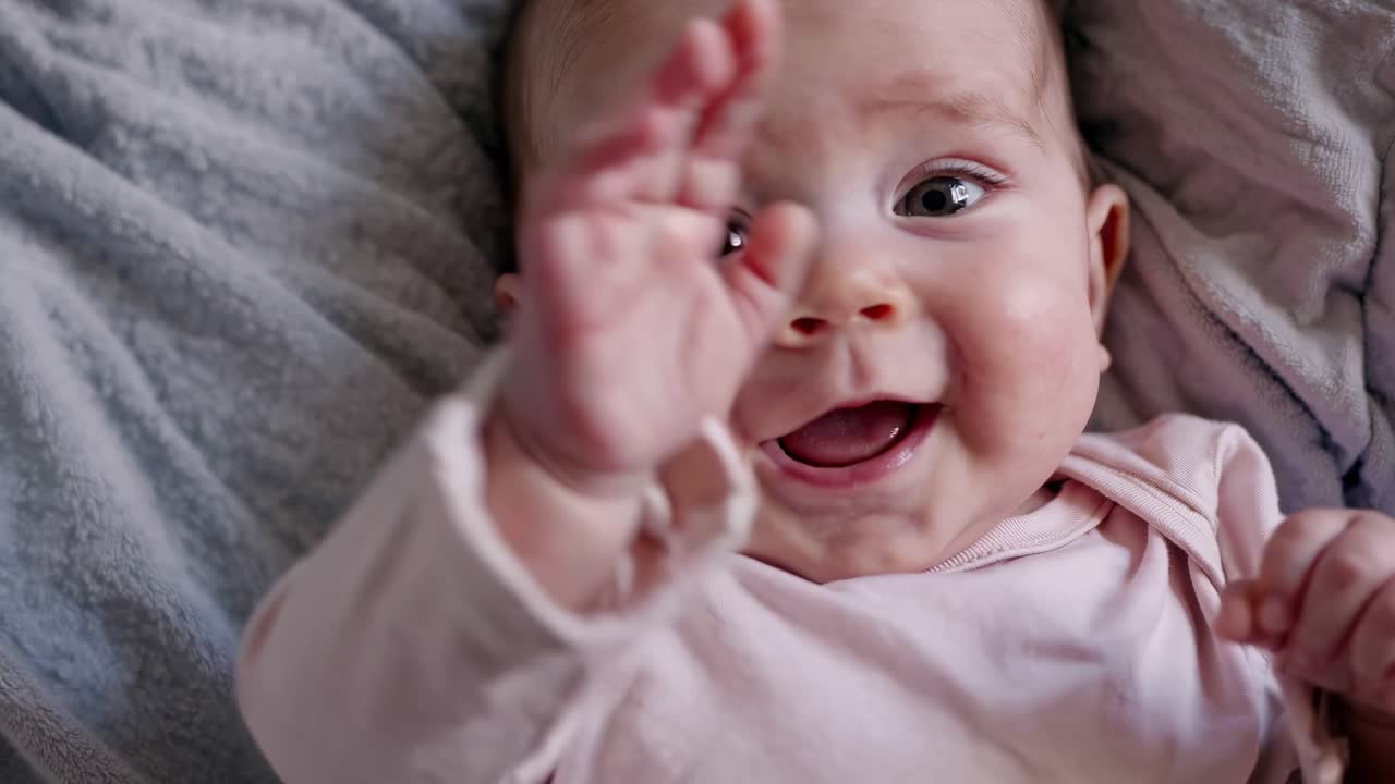Close-up video of a baby lying on a soft blanket, capturing an adorable expression