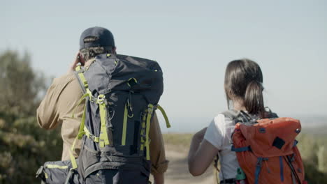 vista trasera de padre e hija con mochilas caminando juntos