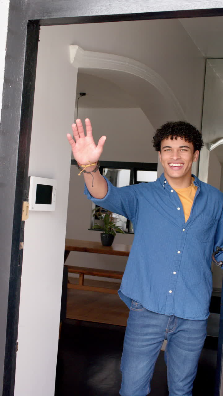 Vertical video of biracial man opening the door and inviting inside a house, slow motion