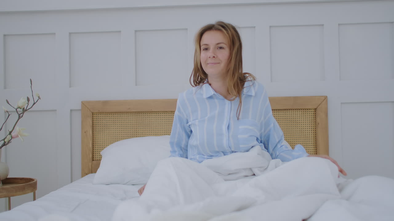 젊은 여자가 아침에 침대에서 웃고 어 일어나서 좋은 아침, 즐거운 아침.