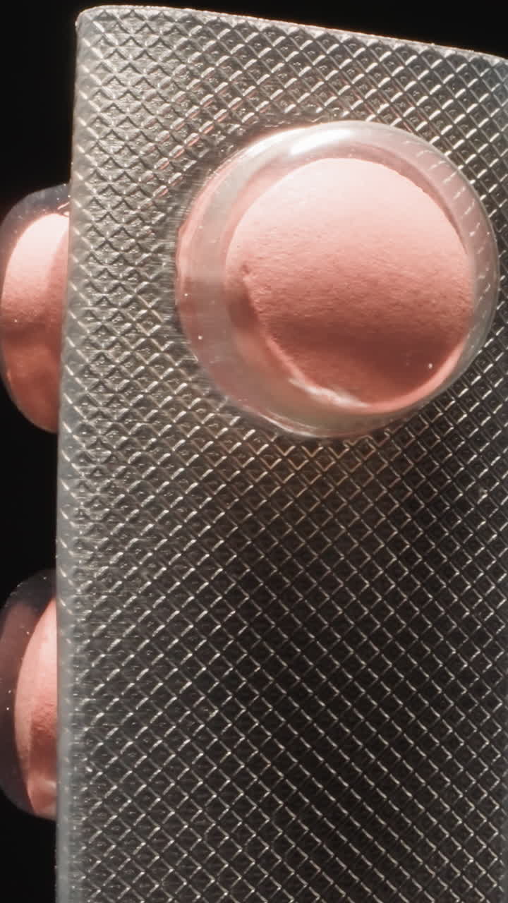 Curved silver blister with pink pills on black background. Effective painkillers prescribed by doctor from headache symptoms. Pharmacy concept macro