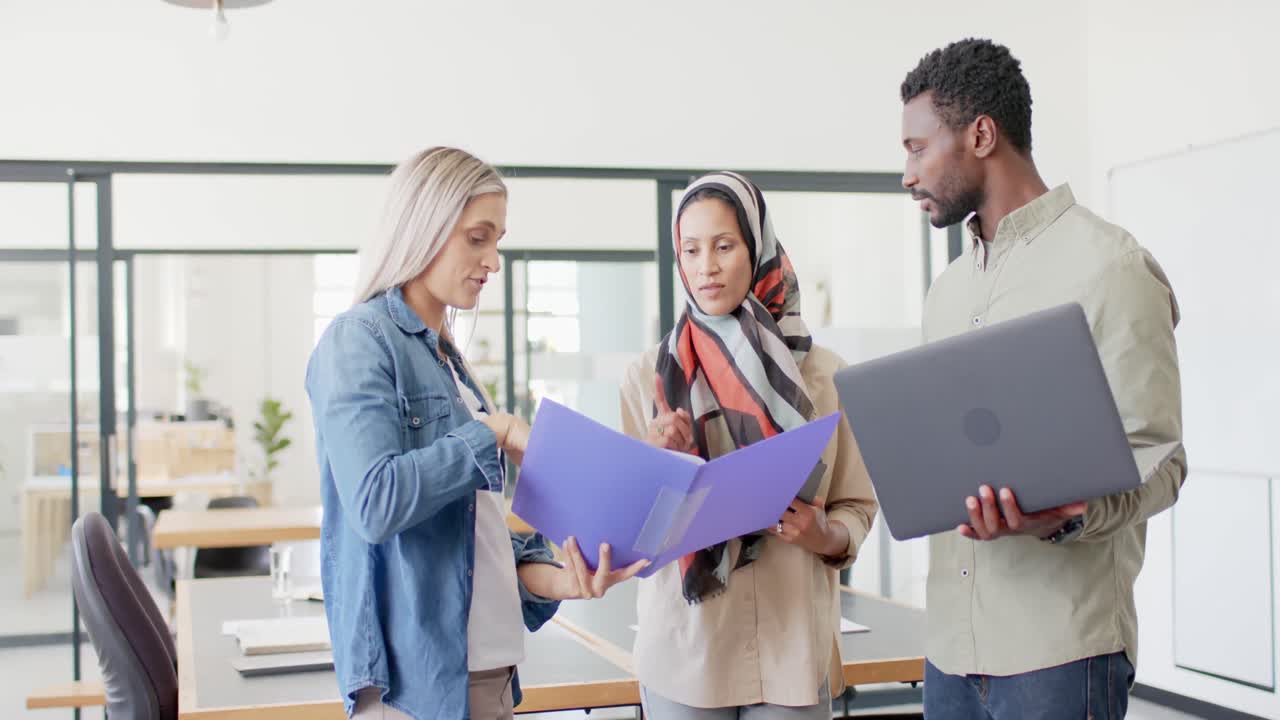 Indaffarati e diversi professionisti che discutono di lavoro con laptop in ufficio al rallentatore