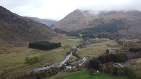 aerial view above the valley between the green hills and the river of the misty and misty scottish highlands