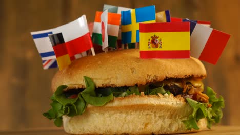 fresh burger with small flag of many countries on top of them with toothpicks. yummy hamburger fast rotating.