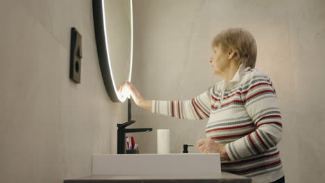 elderly woman cleaning bathroom mirror