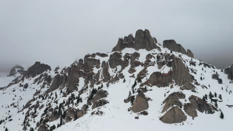 Misty-Montañas-Ciucas-Cubiertas-De-Nieve-Con-Picos-Rocosos-Y-árboles-De-Hoja-Perenne