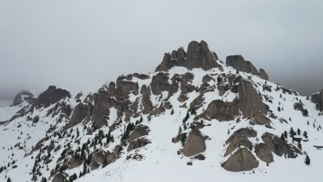 misty snow-covered ciucas mountains with rocky peaks and evergreens