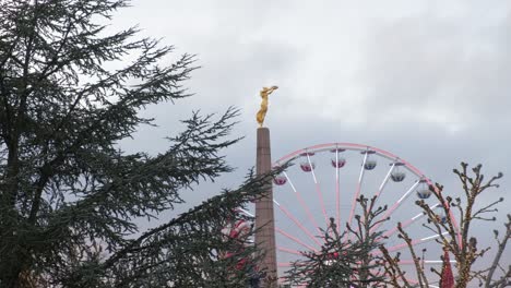 ferris wheel next to golden lady statue in christmas time in city centre of luxembourg - from distant