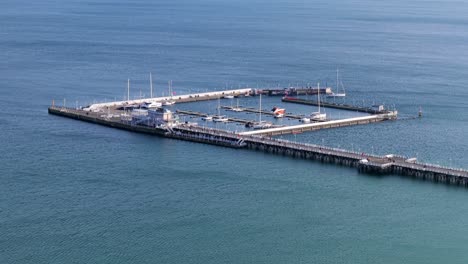 aerial winter orbit of sopot pier, marina, beach, and boats leaving the harbor, calm empty blue ocean water