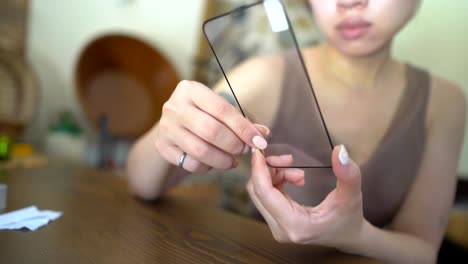 crop woman removing film from protective glass