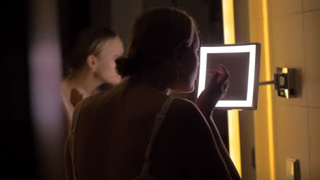 woman looking in bathroom mirror after applying facial cream