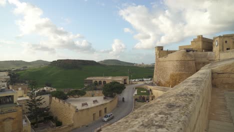 vista escénica de la vegetación de las afueras de victoria con la torre de la fortaleza de cittadella en segundo plano