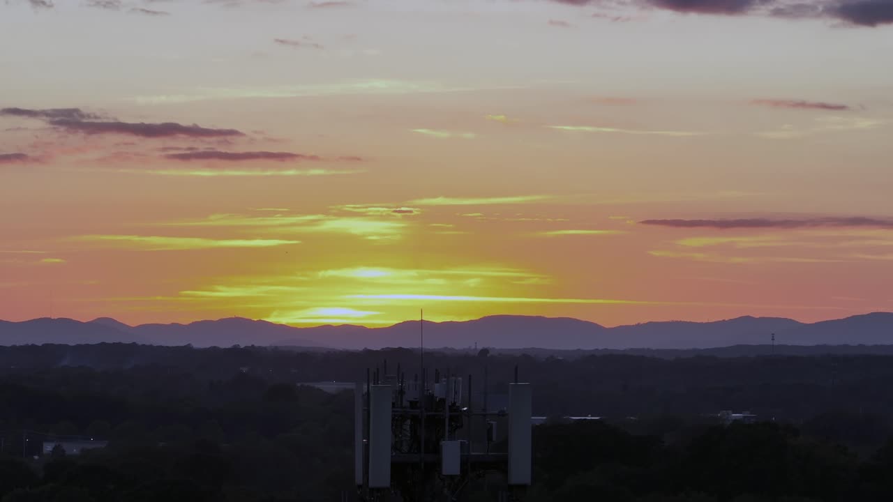 Aerial pedestal up shot of Transmission ratio tower in america during golden sunset. Forest landscape and mountain range in distance. Virginia, USA. Wide shot