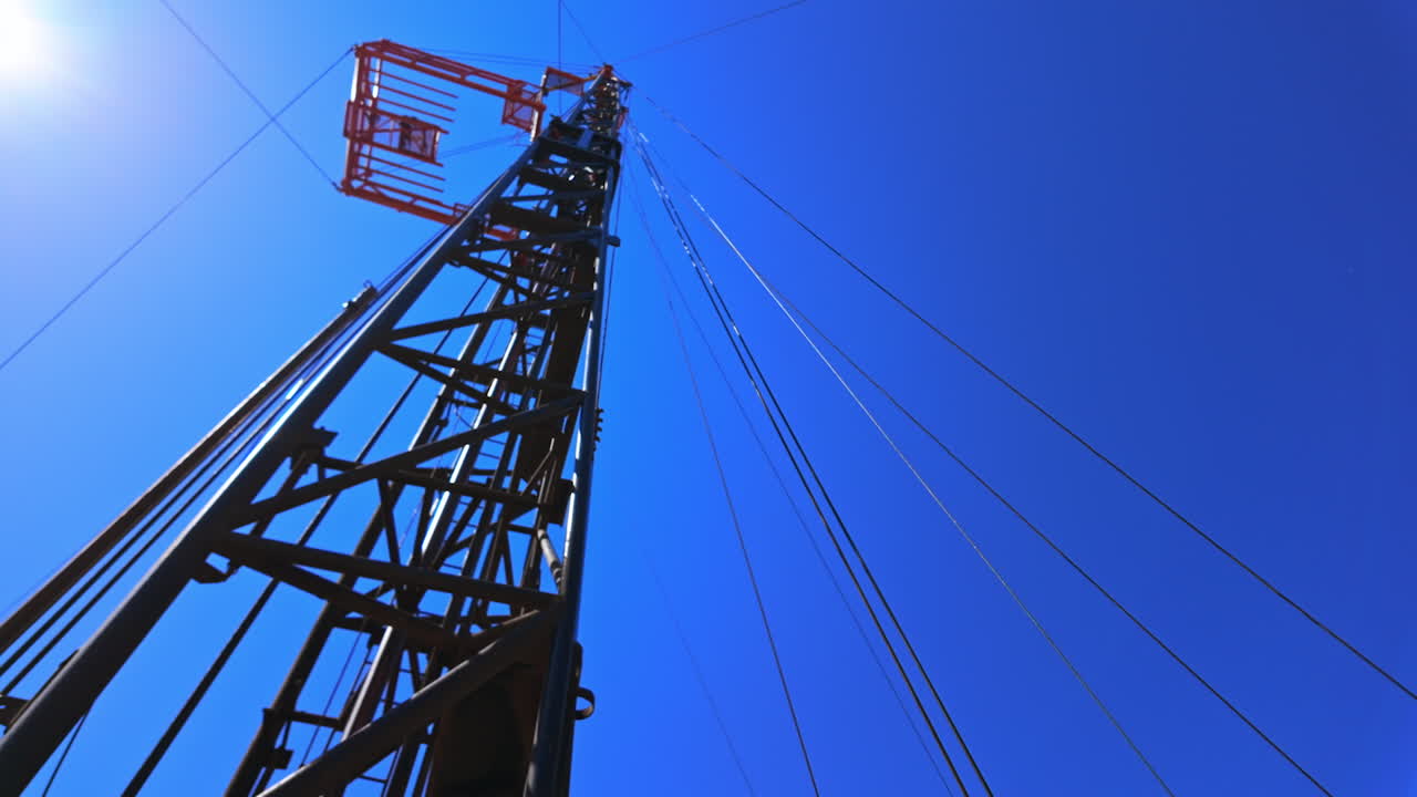 Oil production derrick with the wires attached. Low angle view at the metal tower drilling oil in the field.