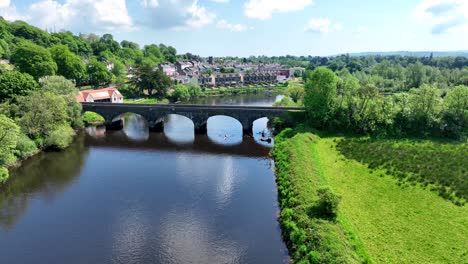 scenic view of a bridge over a river with rowing boats near a town