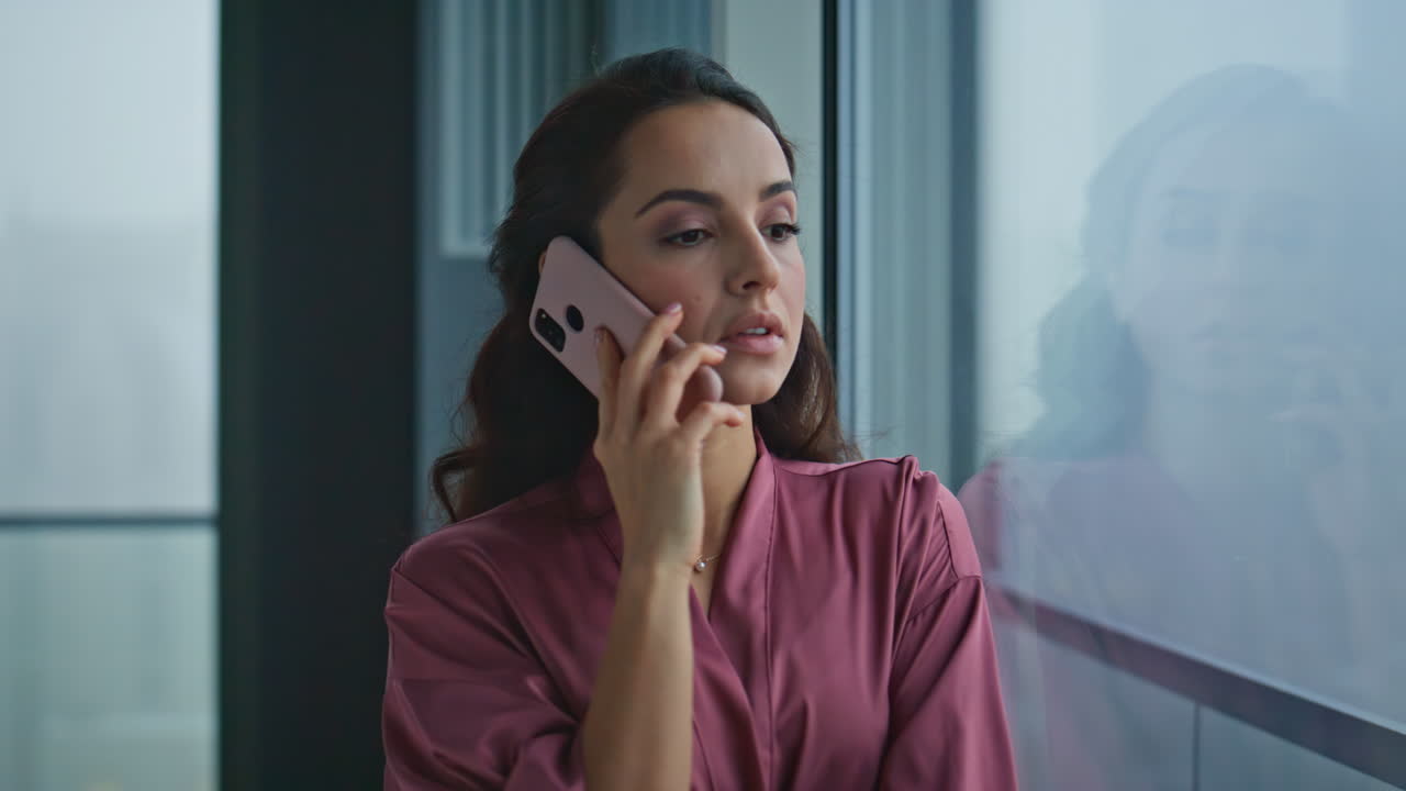 mujer doméstica llamando a un teléfono inteligente en una ventana panorámica plano de primer plano. dama esperando