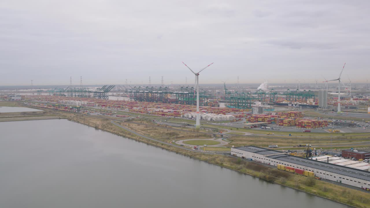Cargo cranes in port of Linkeroever, Belgium, with wind turbines, aerial view
