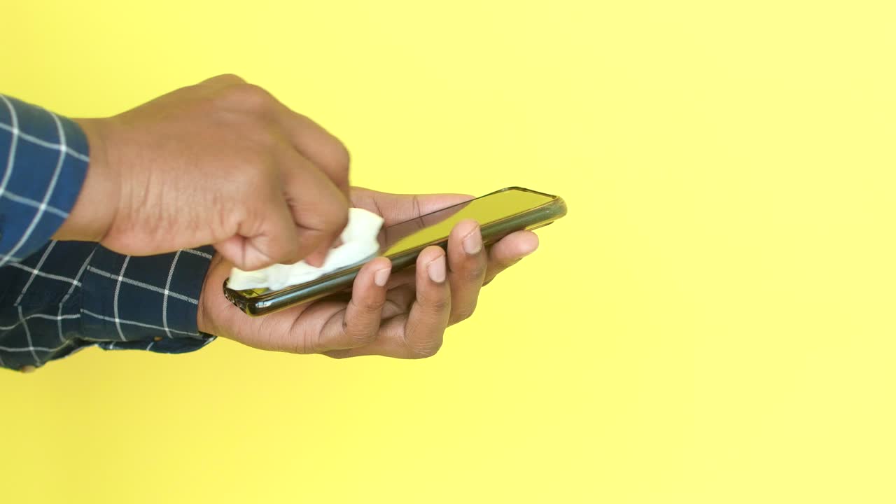 hombre limpiando la pantalla de su teléfono con una toalla