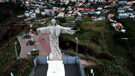 vista aérea orbitando la estatua monumental de cristo rey con vistas a la costa de madeira desde la ladera de la isla