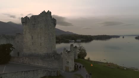 aerial uprising shot of old castle at a lake while sunset reflecting on water surface