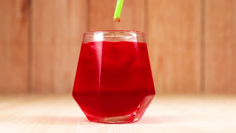 bebida roja en vaso con paja verde que se agita