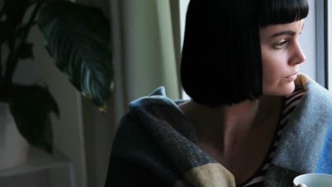 mujer envuelta en una manta tomando café 4k