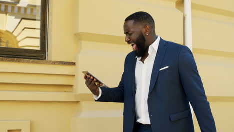 happy businessman receiving good news on tablet outside