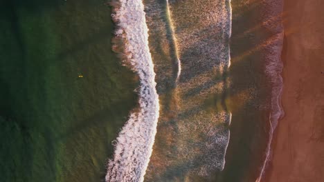 birds eye pov waves breaking at sandy beach