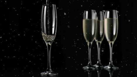 animation of white specks floating over glasses of champagne on black background