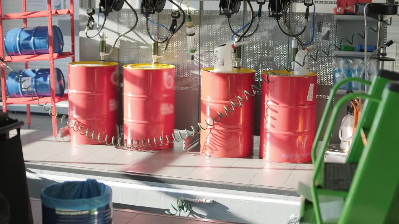 현대 자동차 서비스 워크에서 끔하게 배열 된 은 오일 배럴, 조직 된 장비와 함께 산업 설정, 전문 자동차 유지 보수 및 저장 솔루션을 강조합니다.