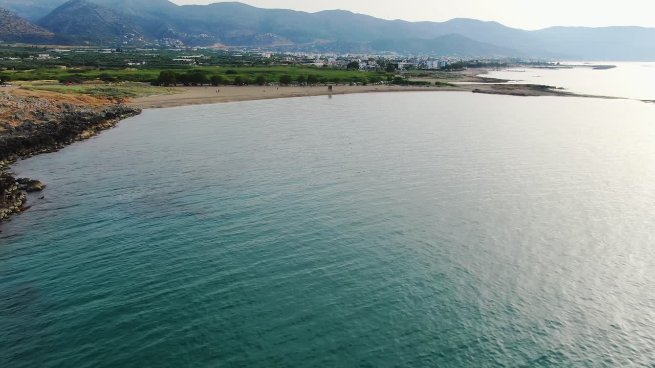 High aerial view above turquoise water near beach towards mountains, Crete, Greece